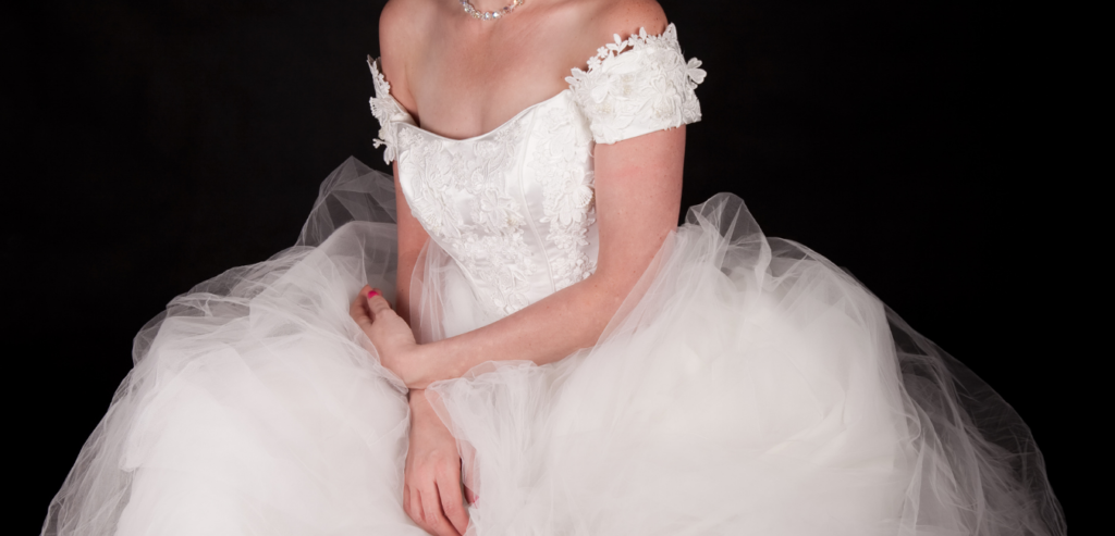 A wedding dress with n off the should fitted top and full tulle skirt