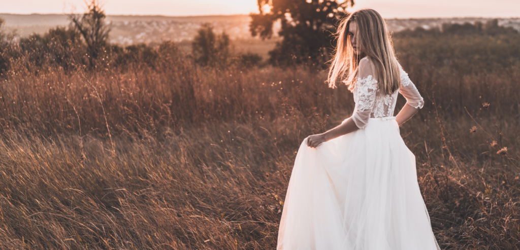 Boho bride runs through summer field of wheat