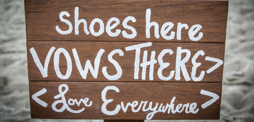 At a beach wedding, a sign helps guests know where to leave their shoes