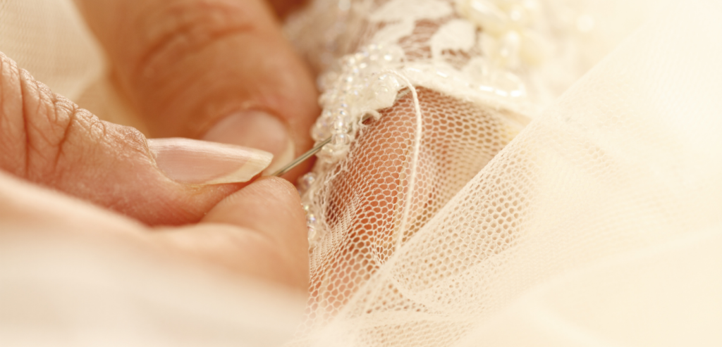 Sewing some extra lace on the edge of a bridal veil